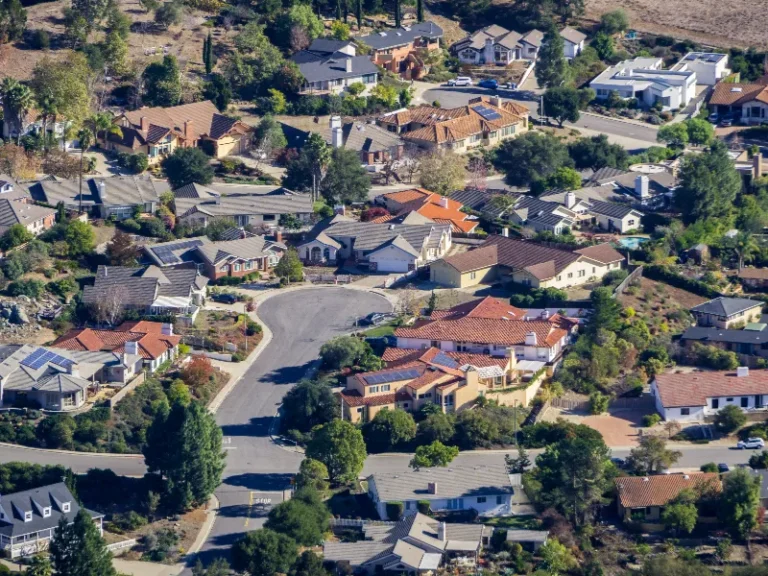 Aerial view of a suburban neighborhood with houses, trees, and winding streets.